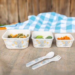 Three food containers with elephant design on a table outdoors, with a checkered cloth in the background.