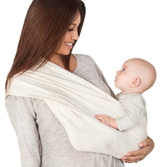Woman holding a baby in a white sling against a white background