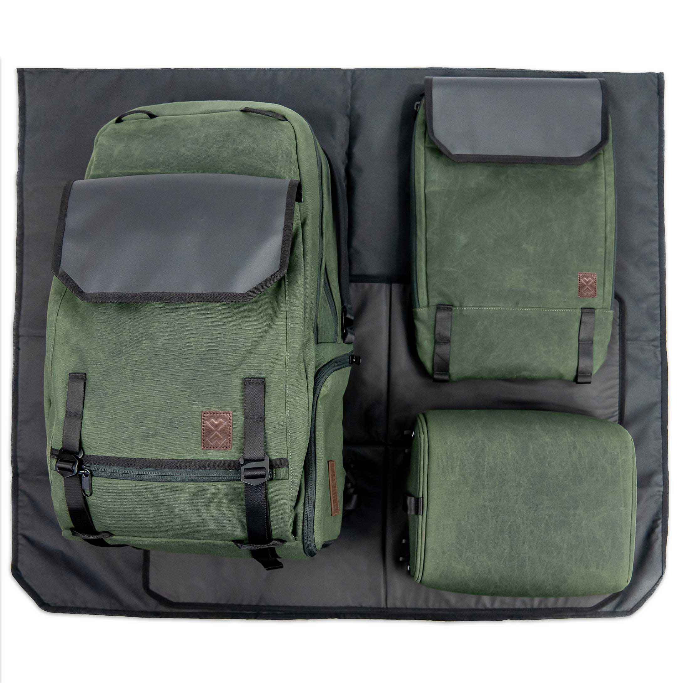 Green backpack and two green bags on a black mat
