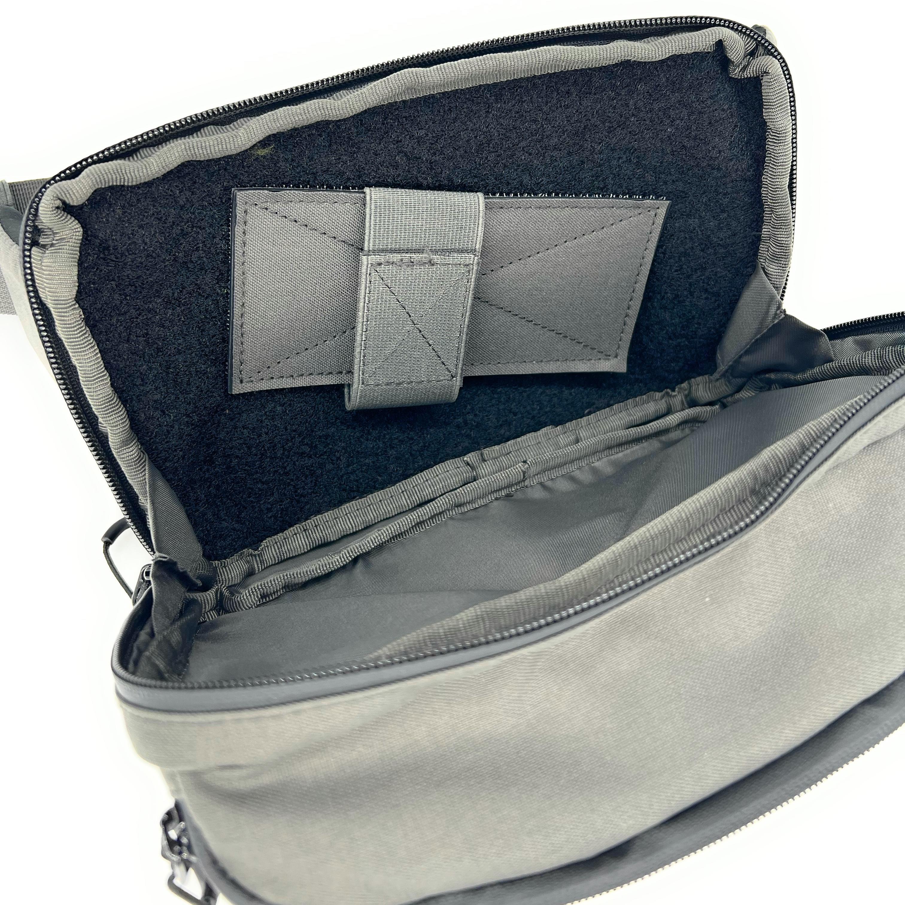 Gray bag with a flap open, revealing interior padding and a strap.