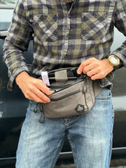 Person wearing a plaid shirt and jeans with a gray waist bag.
