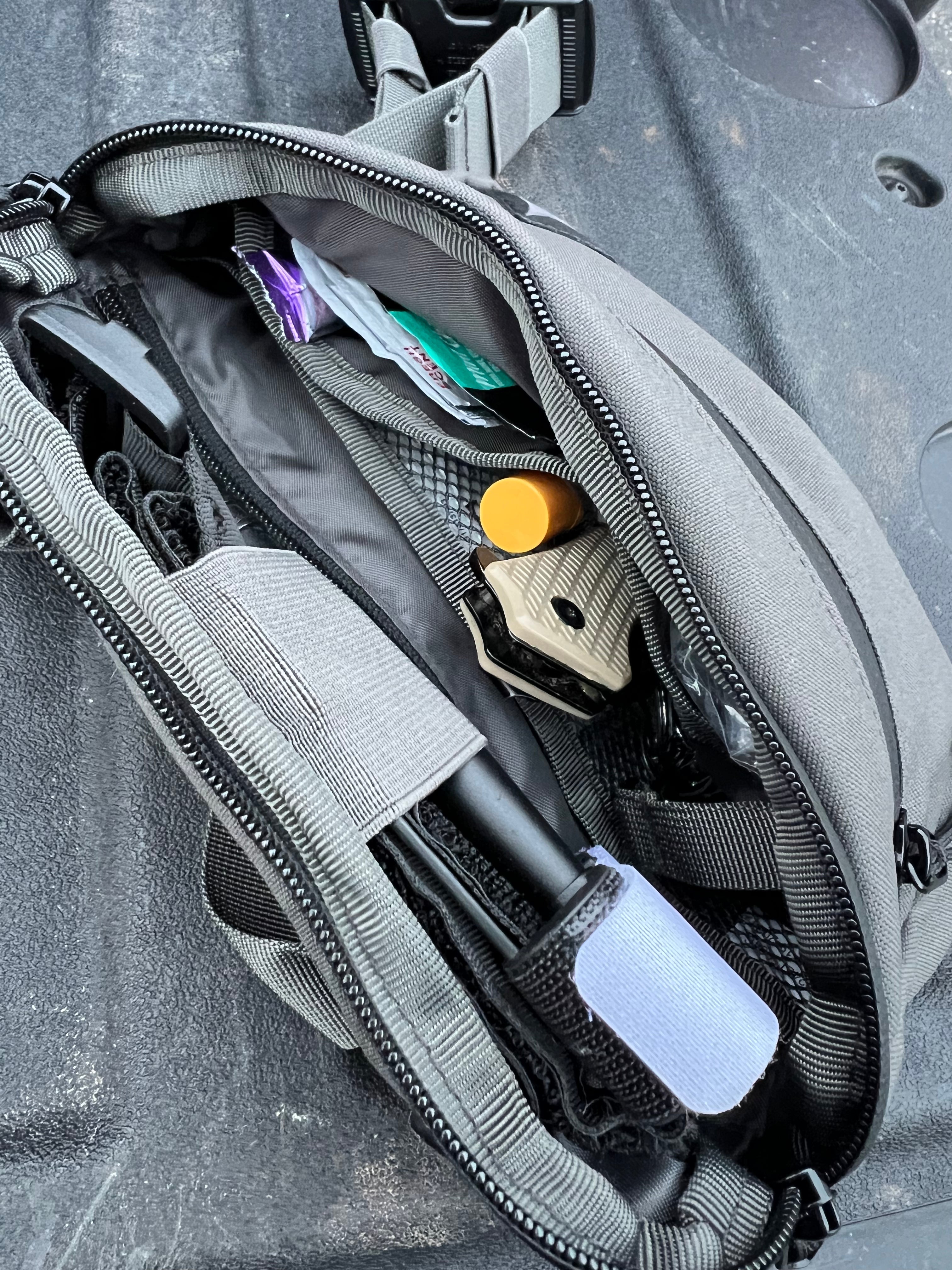Gray tactical pouch with tools and equipment inside on a gray background