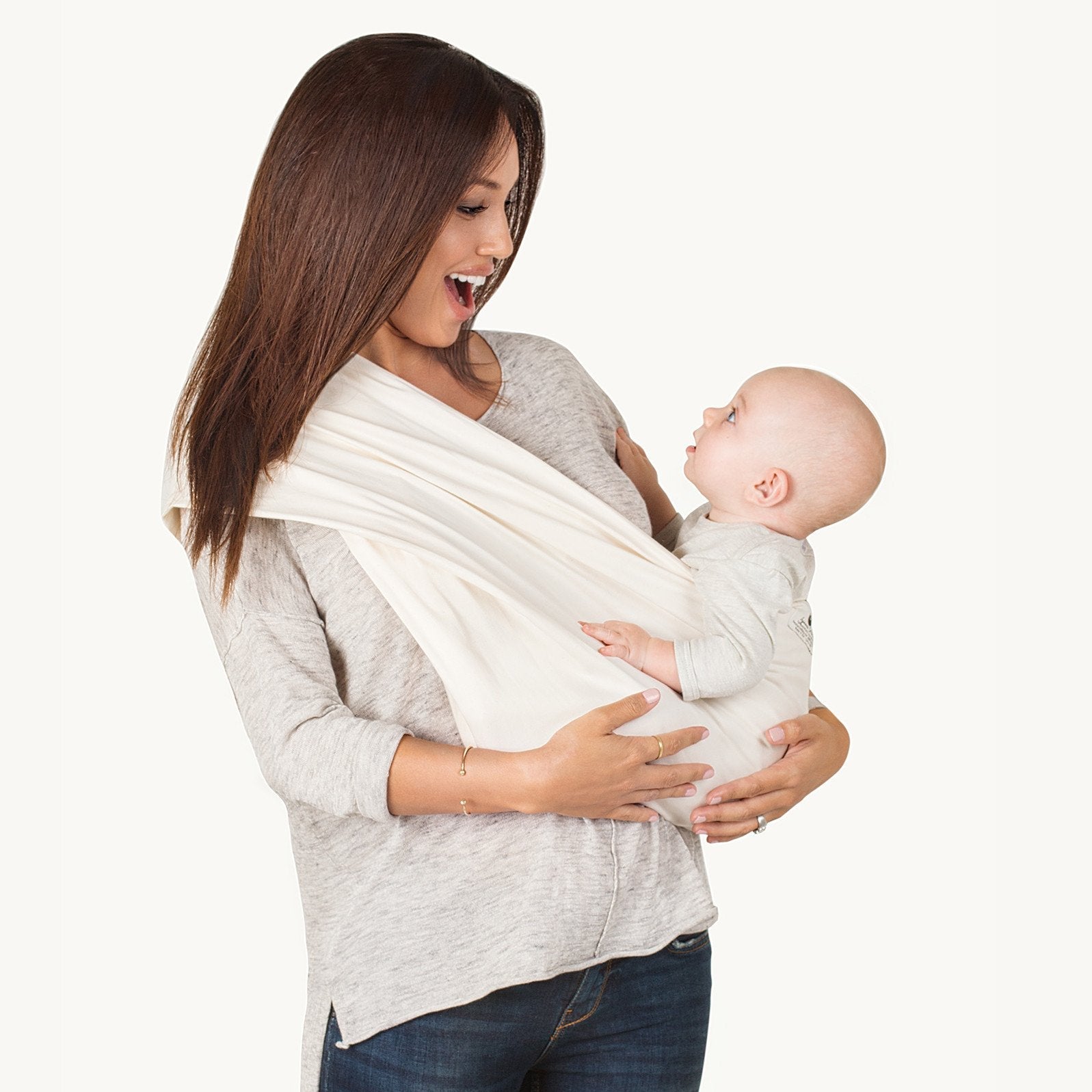Woman holding a baby in a white wrap against a white background