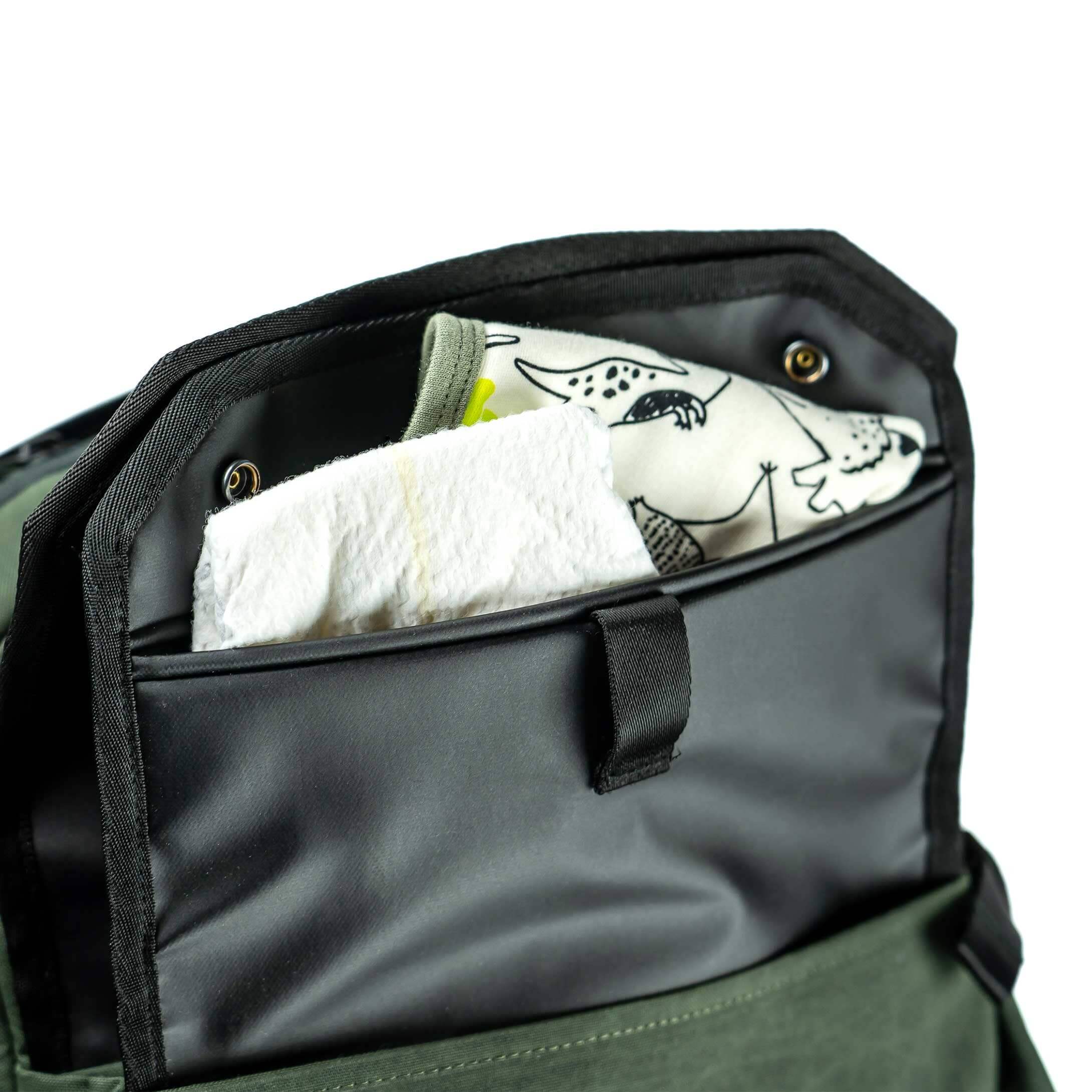 Green bag with a black interior pocket containing a white towel and a cartoon fish design.