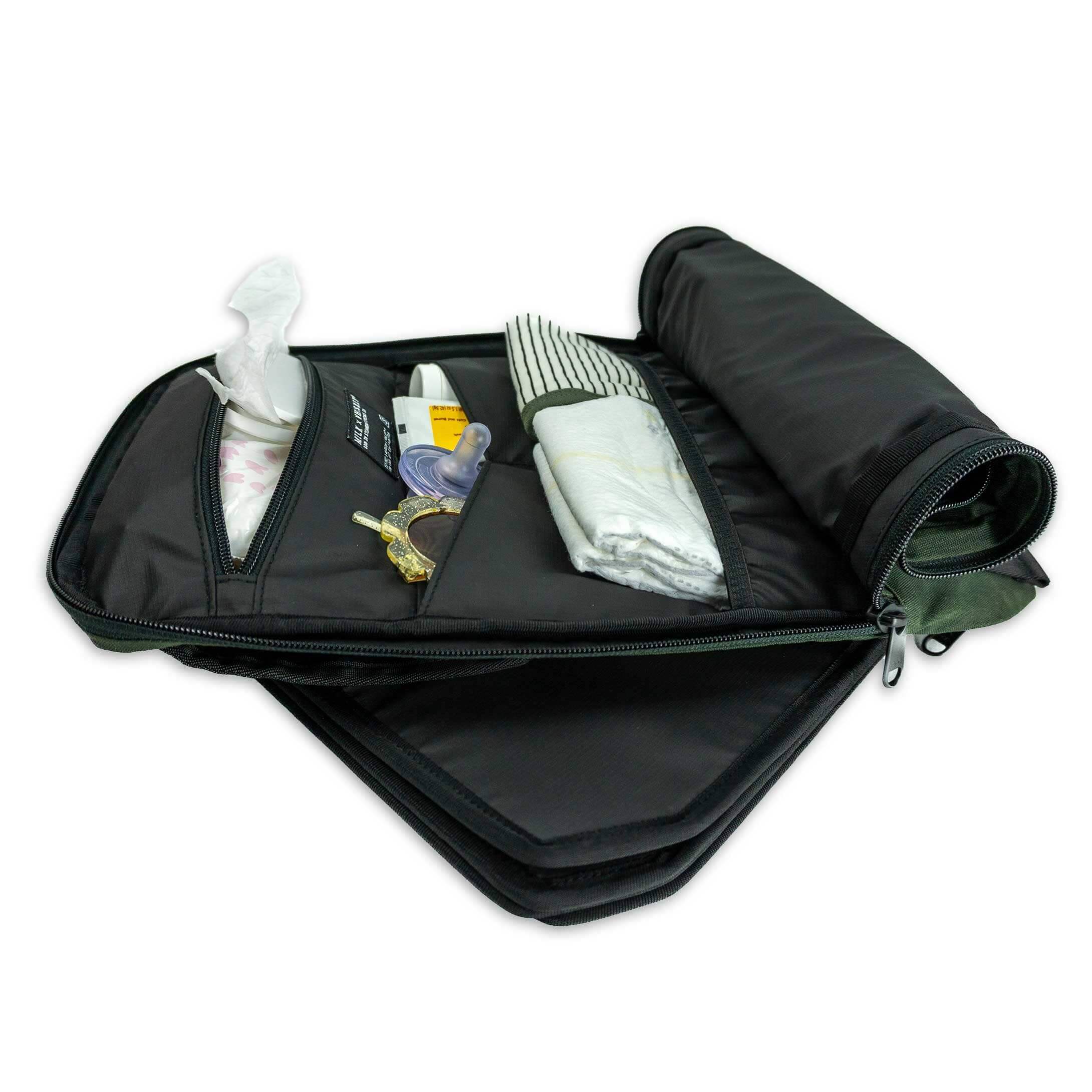 Black travel bag with folded clothes and toiletries on a white background