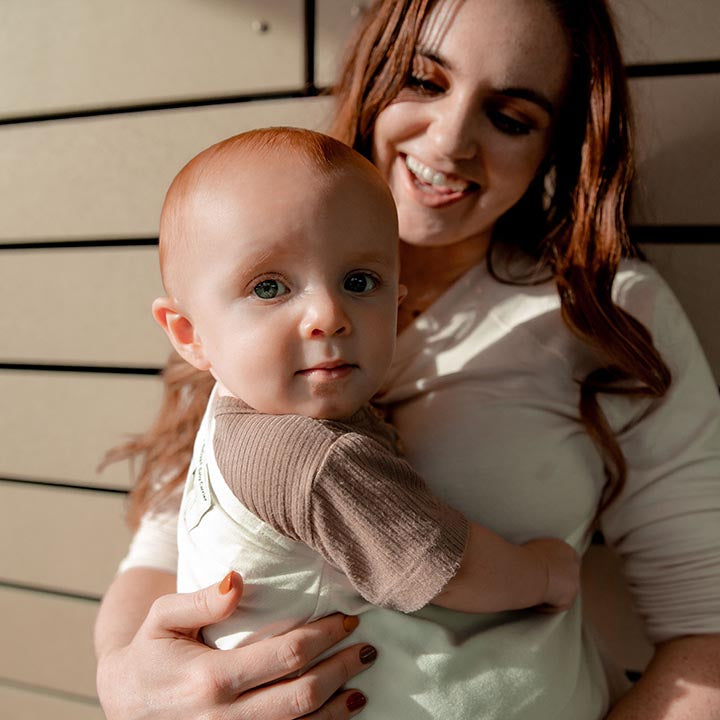 Woman holding a baby with a wooden background