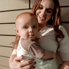 Woman holding a baby with a wooden background
