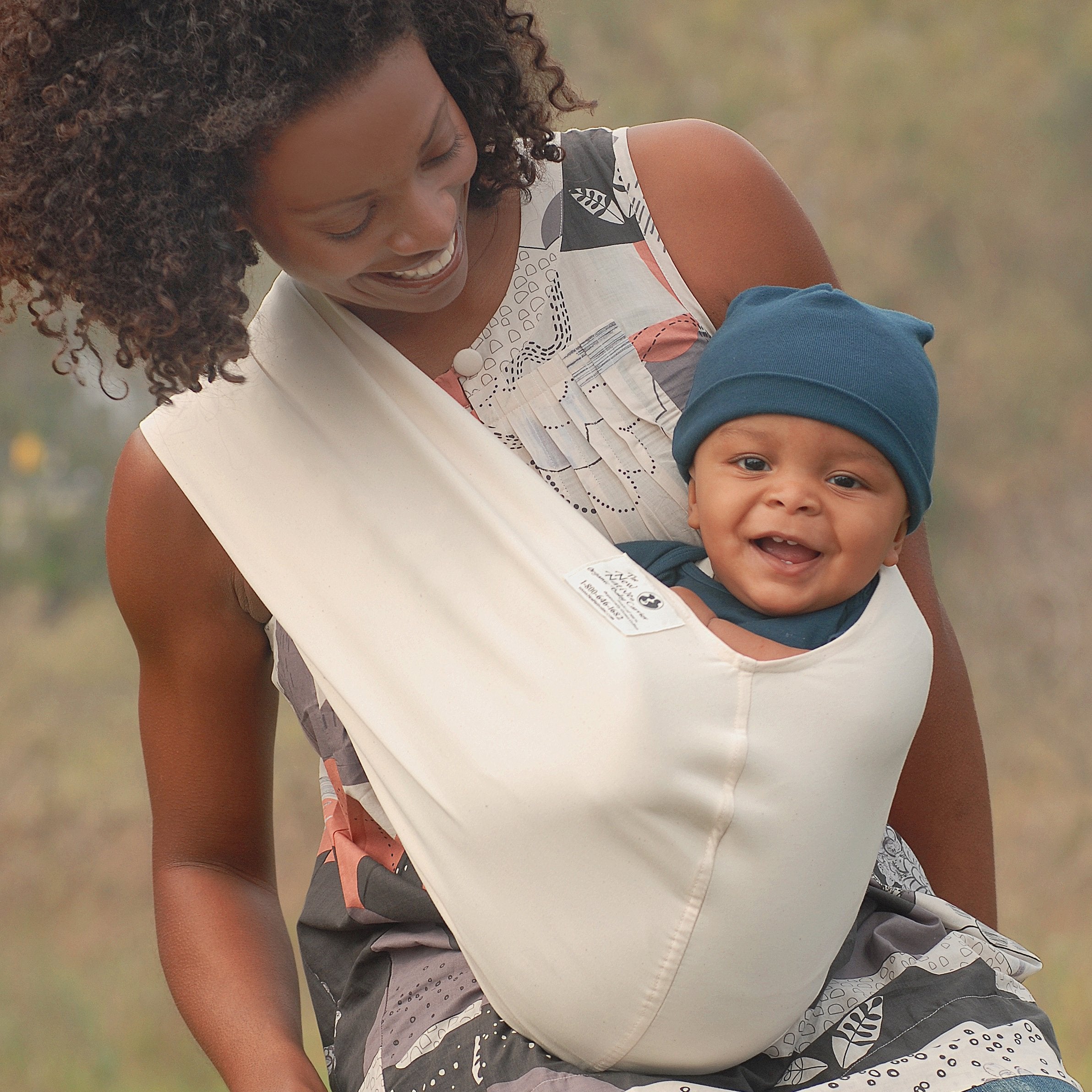 Woman holding a baby in a sling outdoors