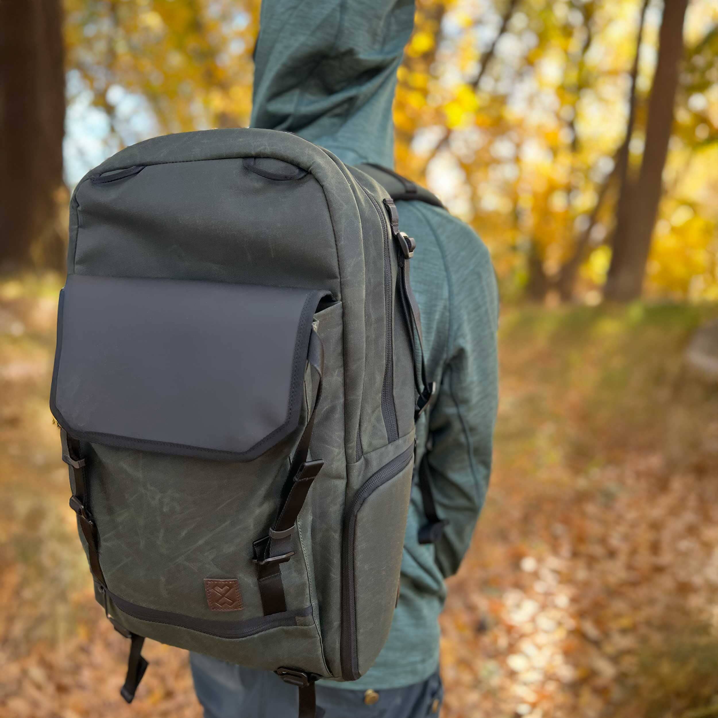 Person wearing a gray backpack in an autumn forest setting